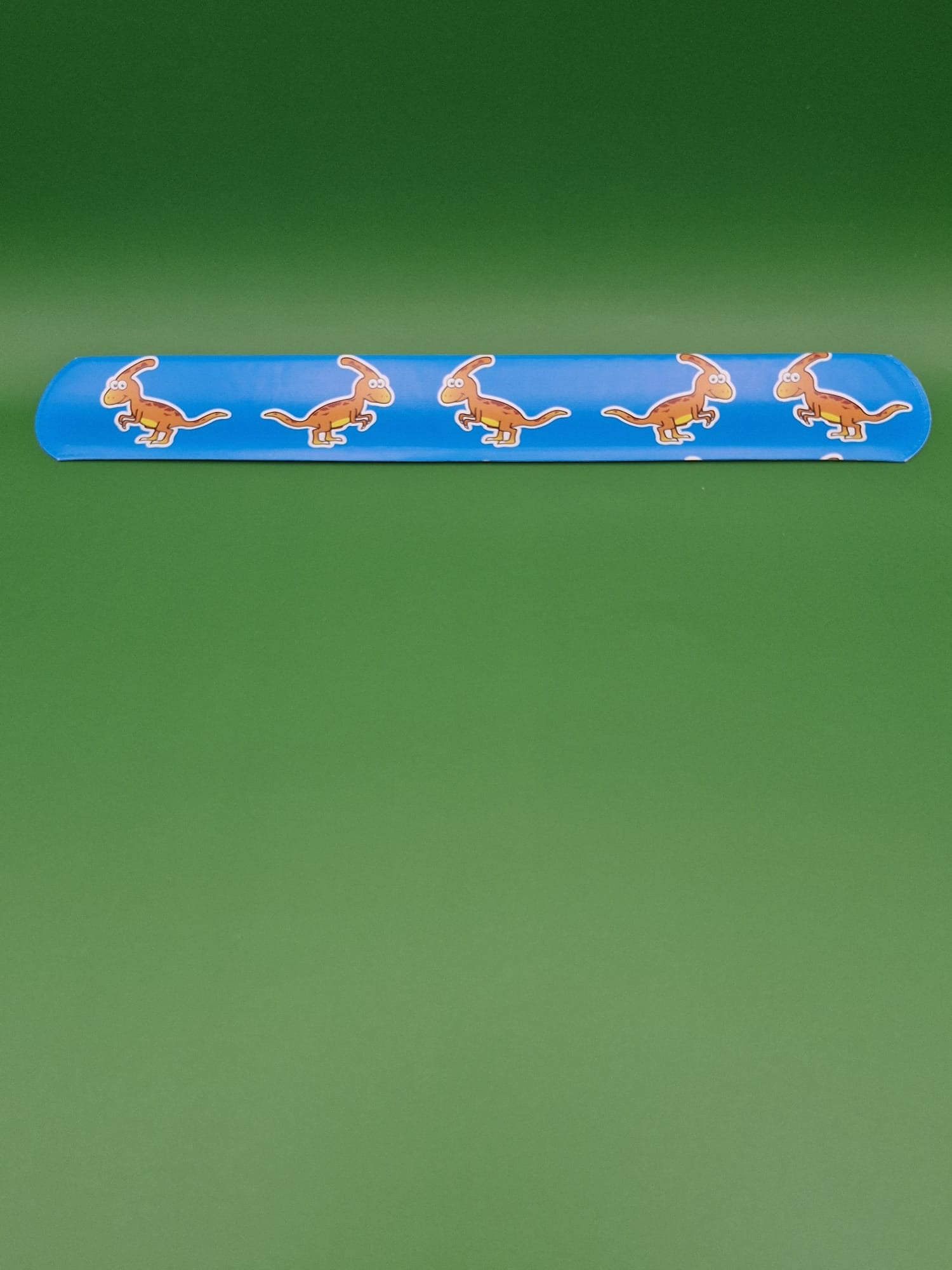 Blue snap bracelet with dinosaur designs on a green background
