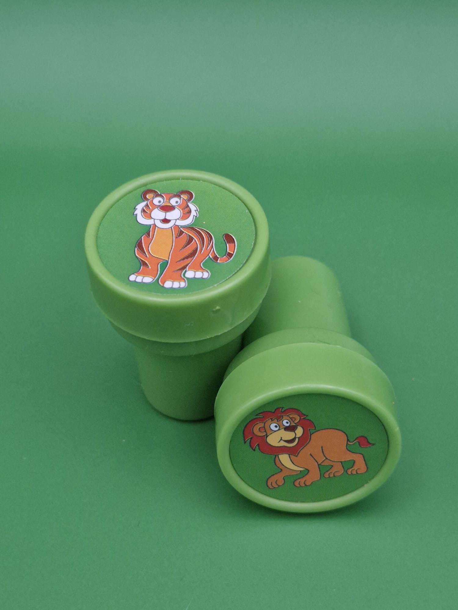 Two green containers with cartoon tiger and lion designs on a green background