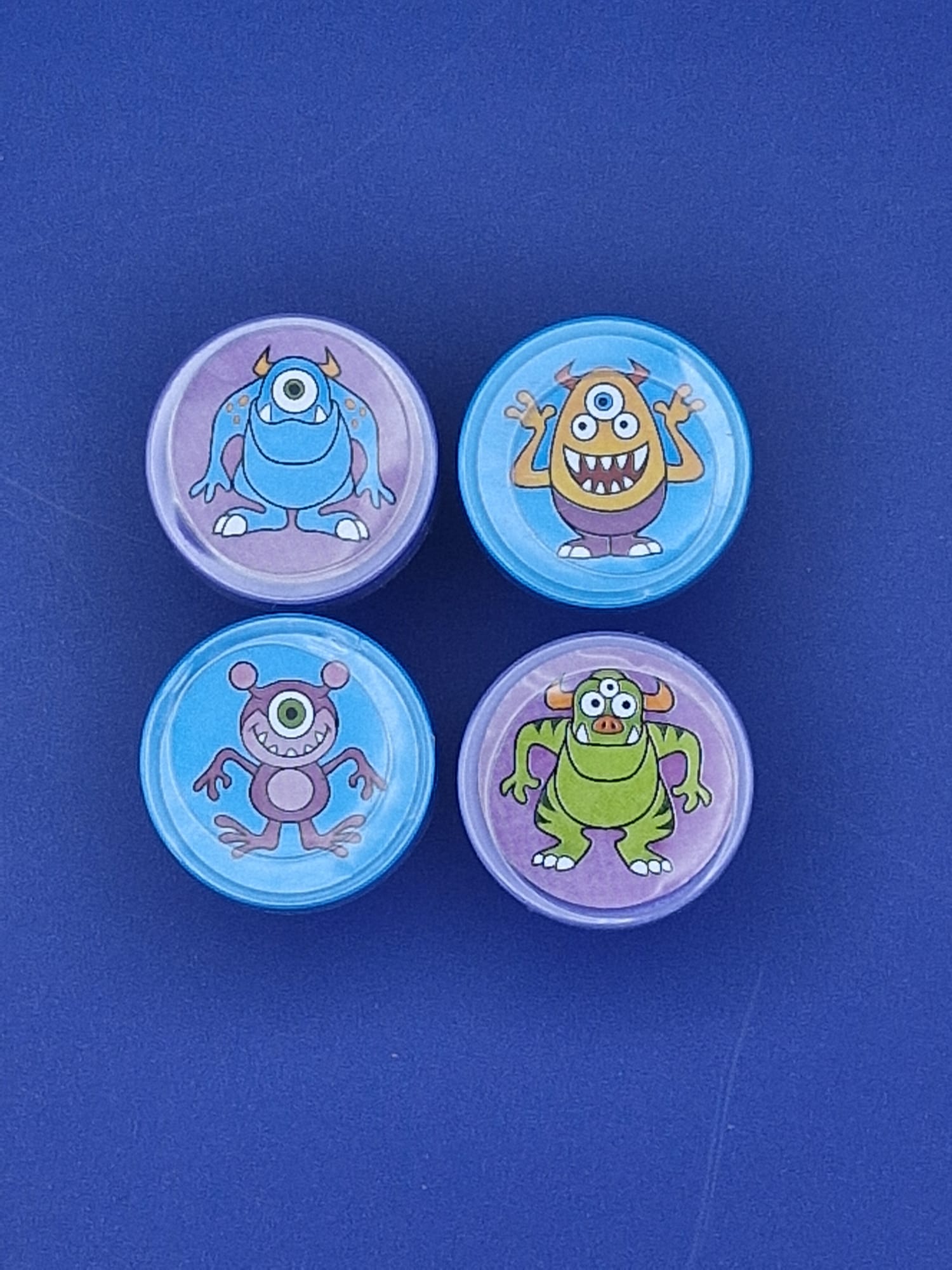 Four colourful stamps with cartoon monster designs on a blue background