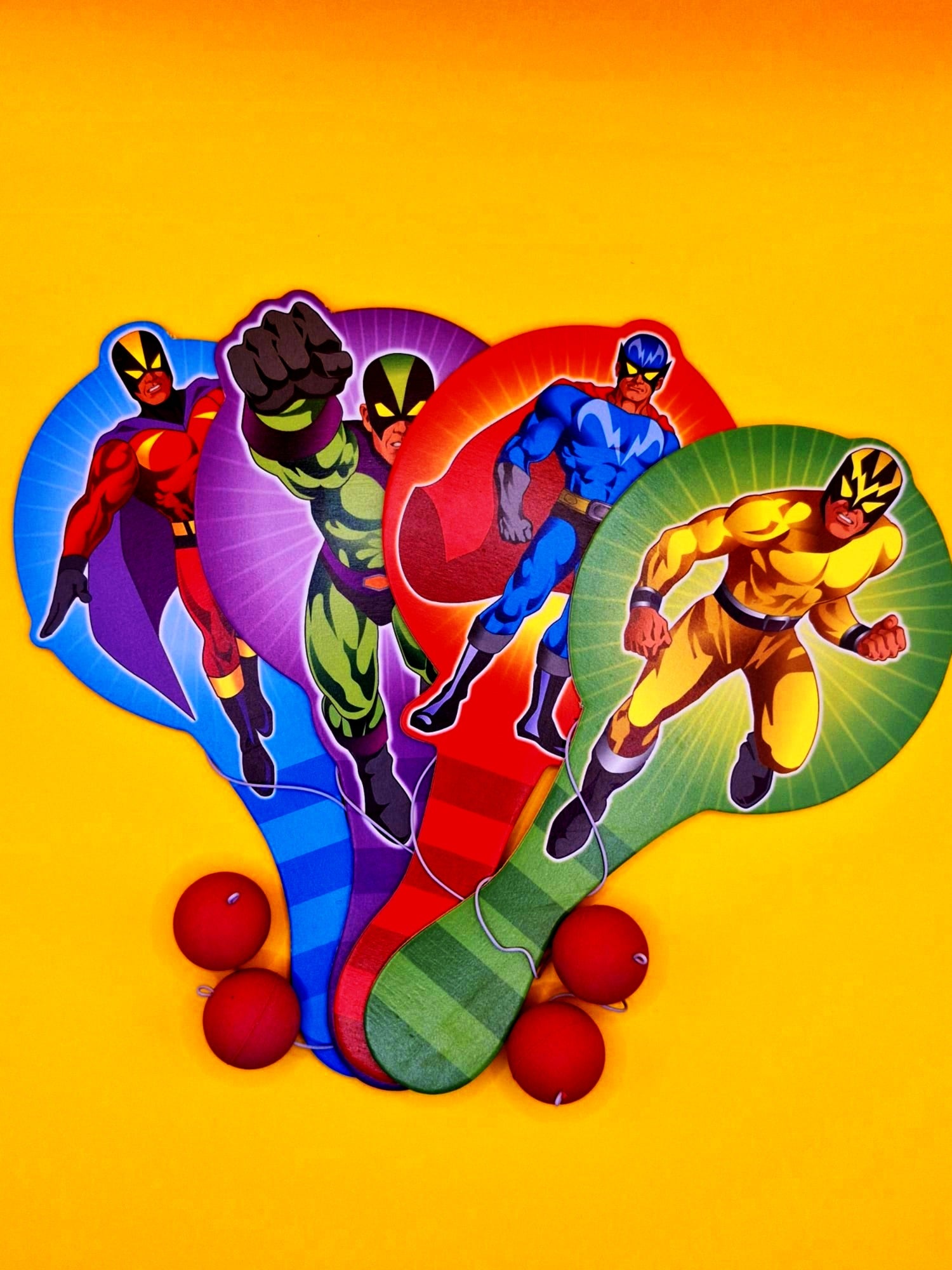 Four superhero figures on colorful oval shapes with red balls below on a yellow background