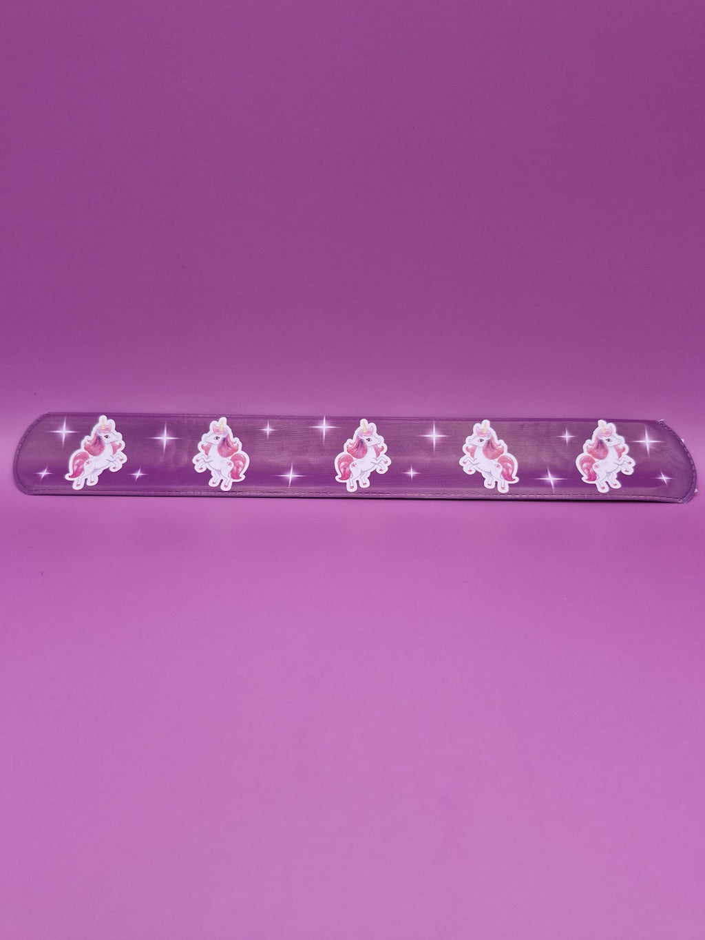 Purple snap bracelet with unicorn designs on a purple background
