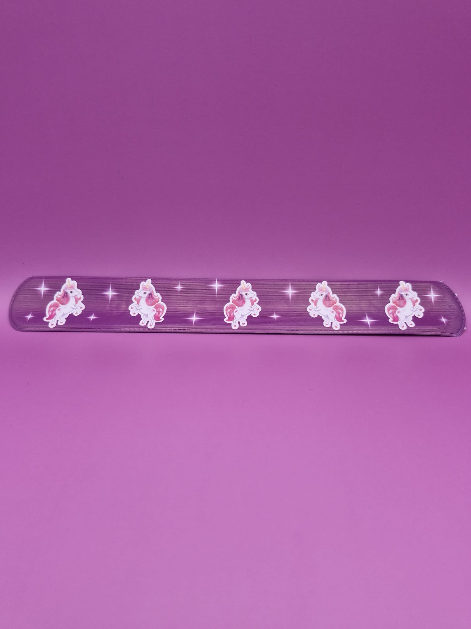 Purple snap bracelet with unicorn designs on a purple background