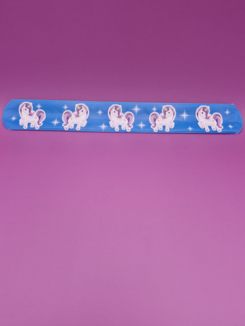 Blue snap bracelet with unicorn designs on a purple background