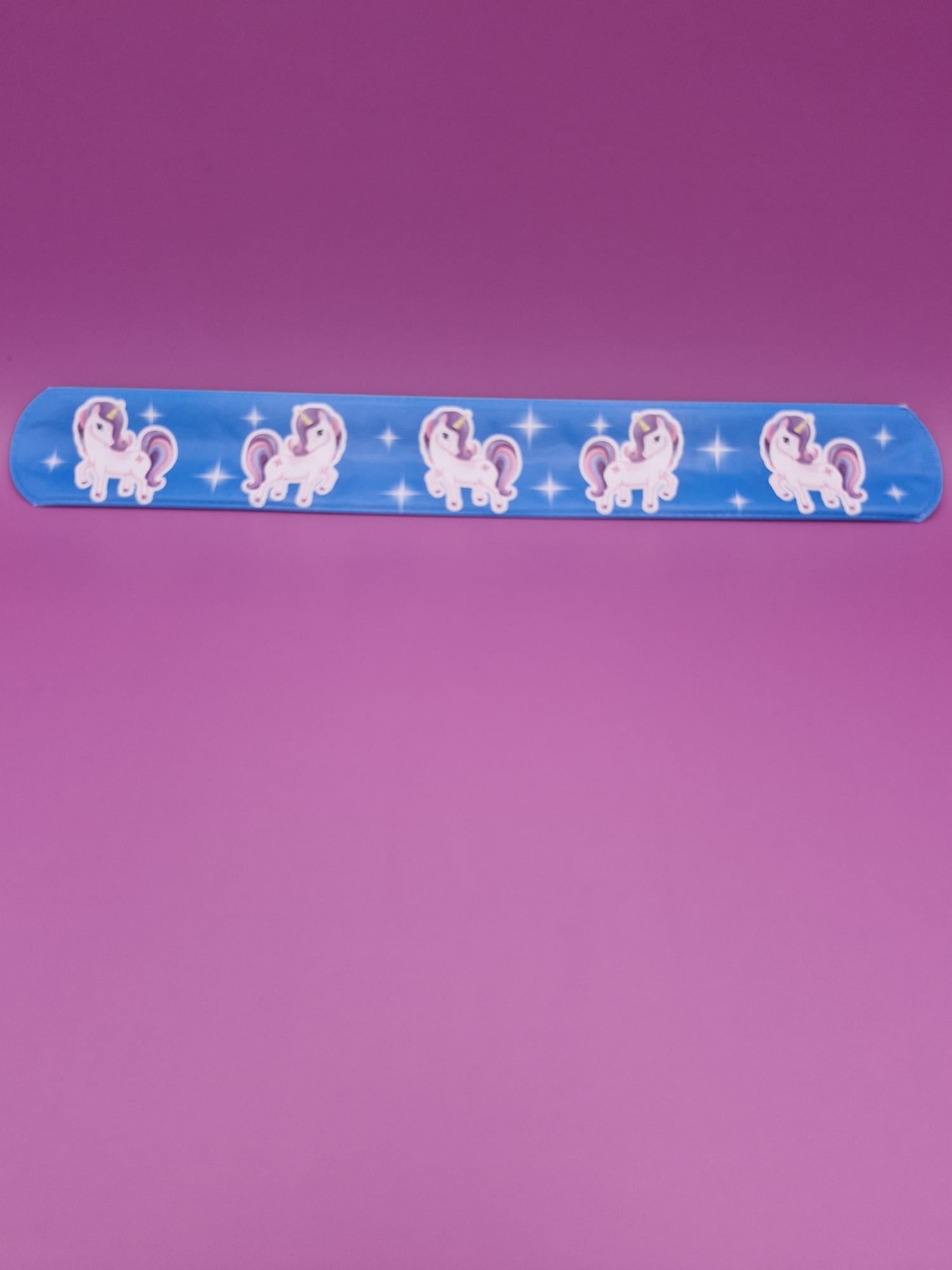 Blue snap bracelet with unicorn designs on a purple background