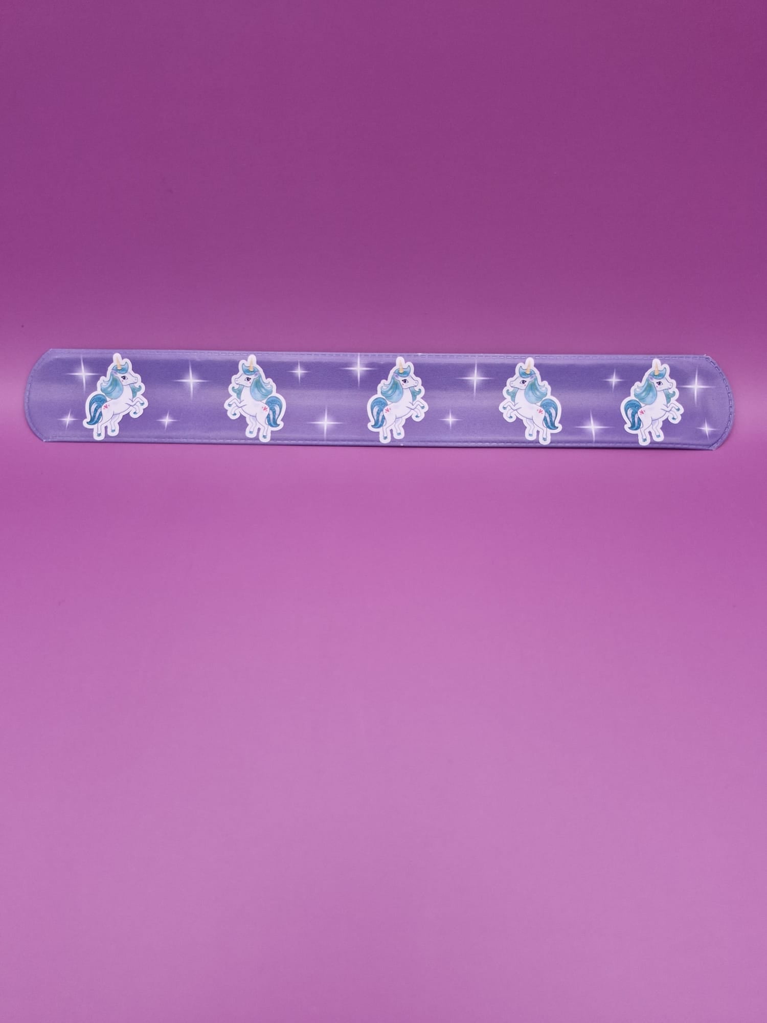 Purple snap bracelet with unicorn designs on a purple background