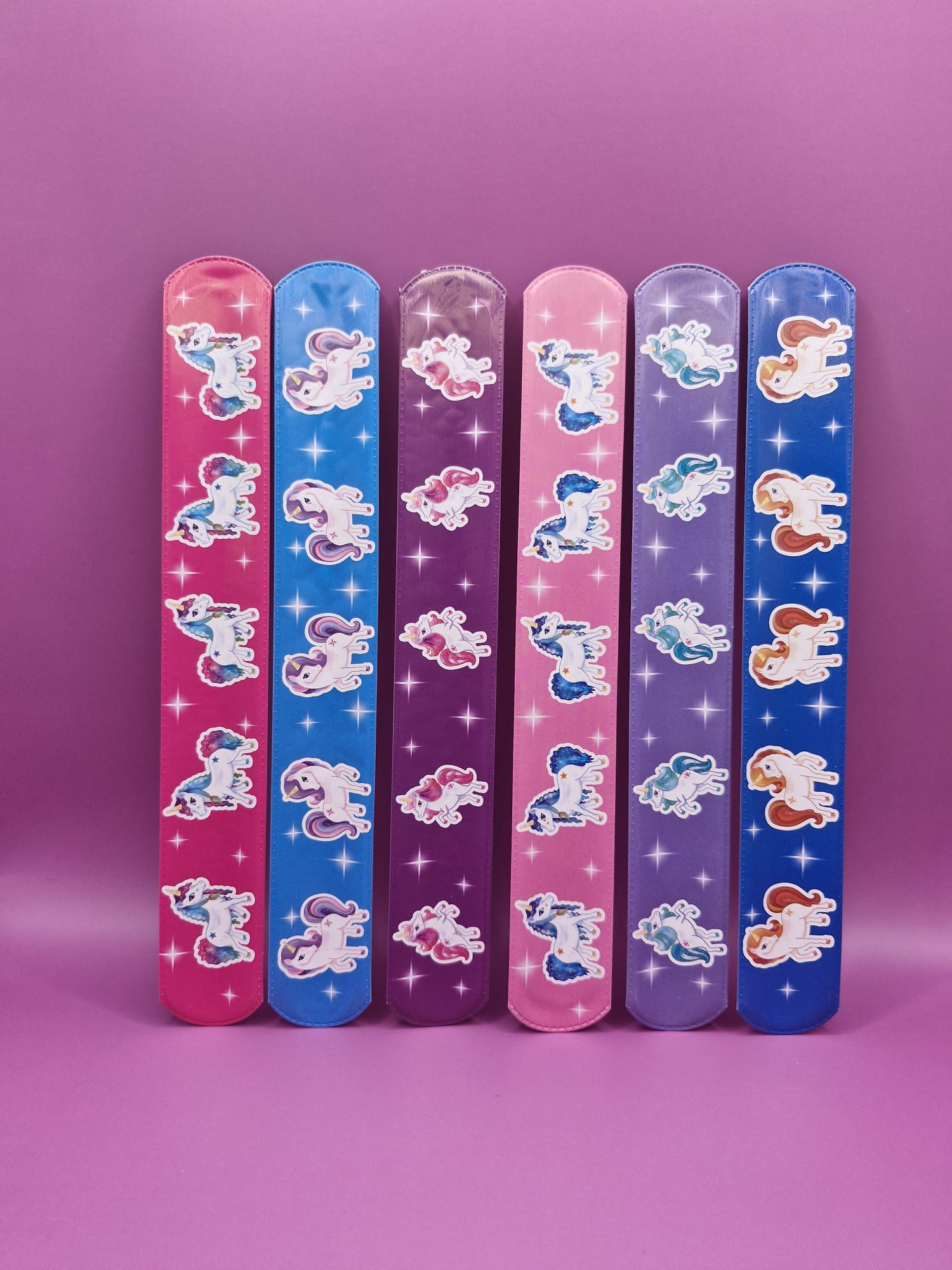 Set of colourful slap bracelets with unicorn characters on a purple background
