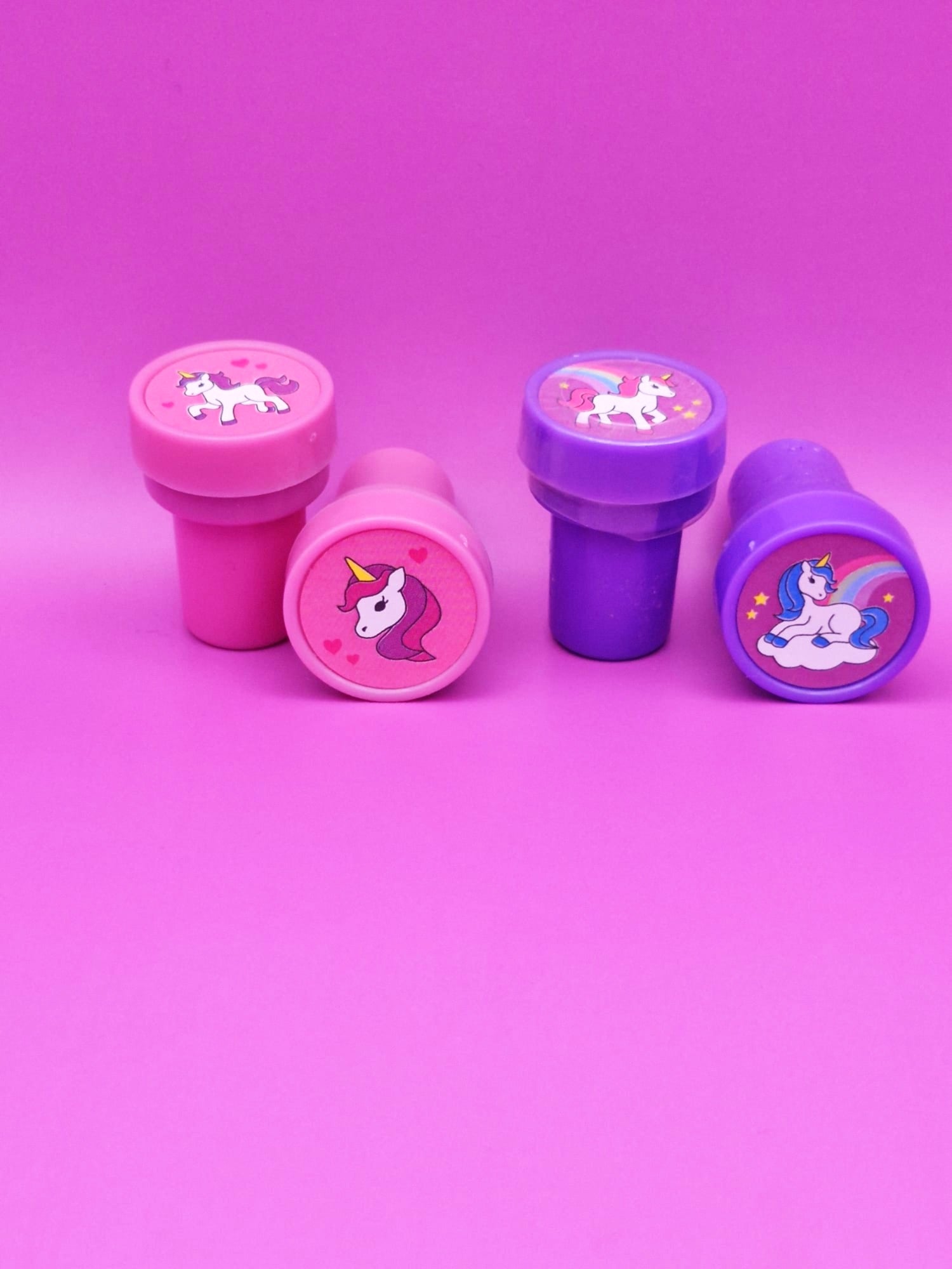 Set of four pink and purple stampers with unicorn designs on a pink background