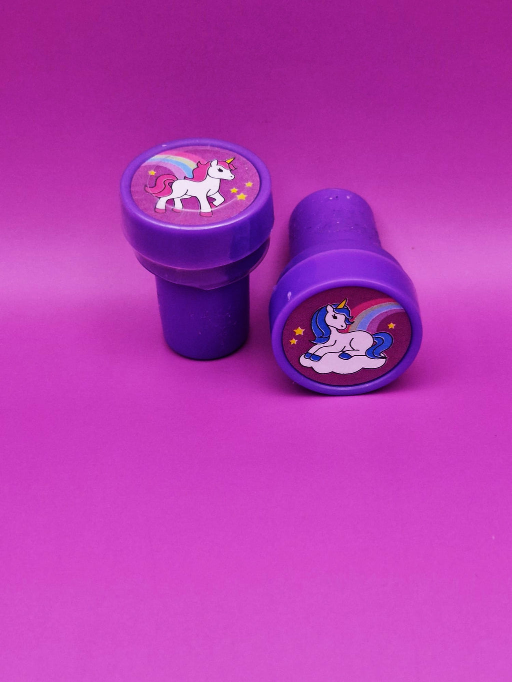 Two purple stampers with unicorn designs on a pink background