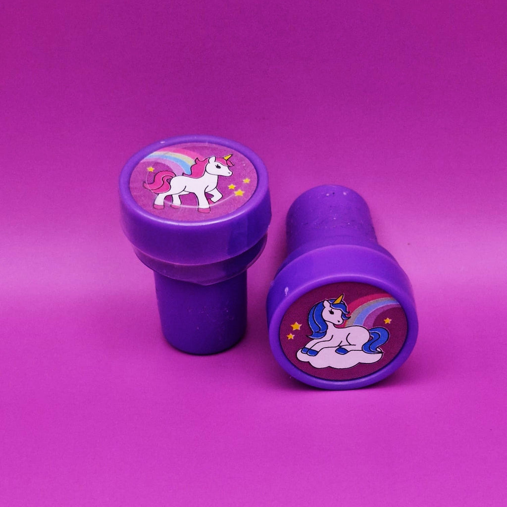 Two purple stampers with unicorn designs on a pink background