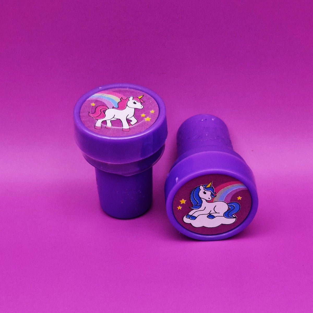 Two purple stampers with unicorn designs on a pink background