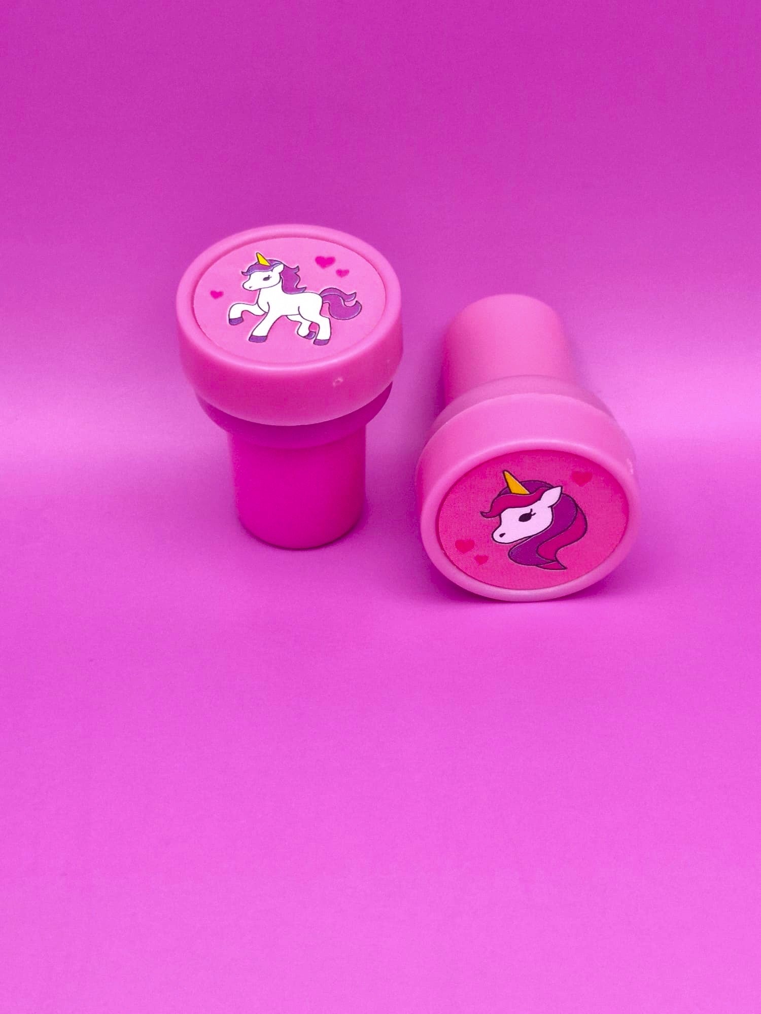 Two pink stampers with unicorn designs on a pink background