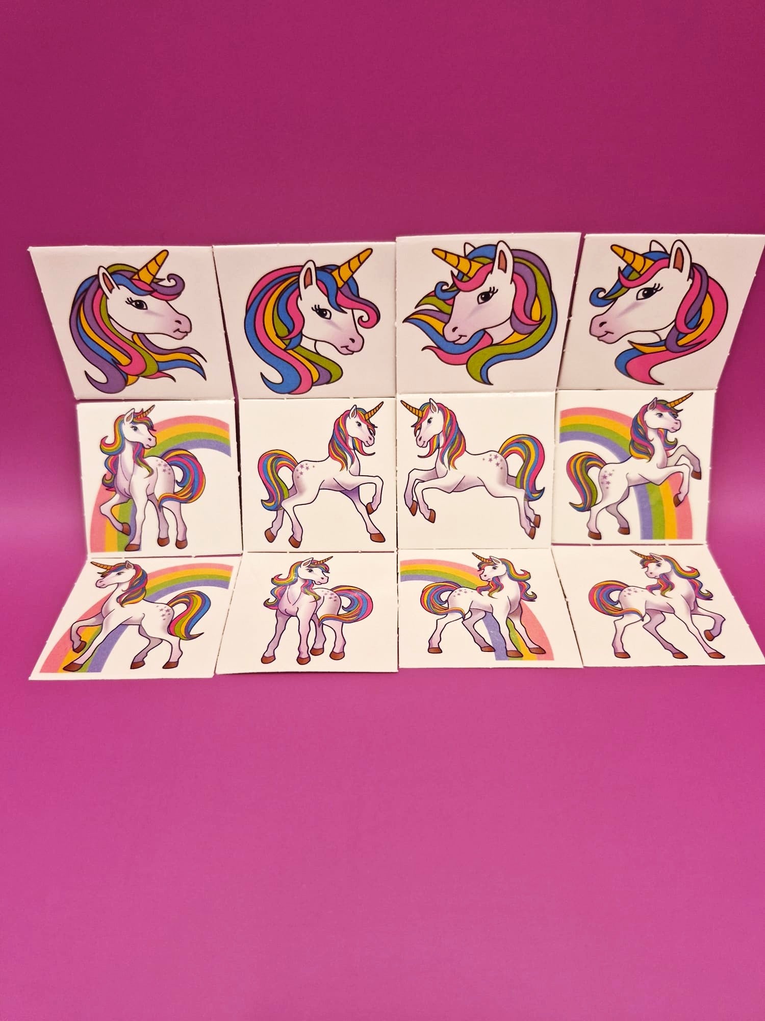 Sheet of unicorn tattooes with multicolored designs on a pink background