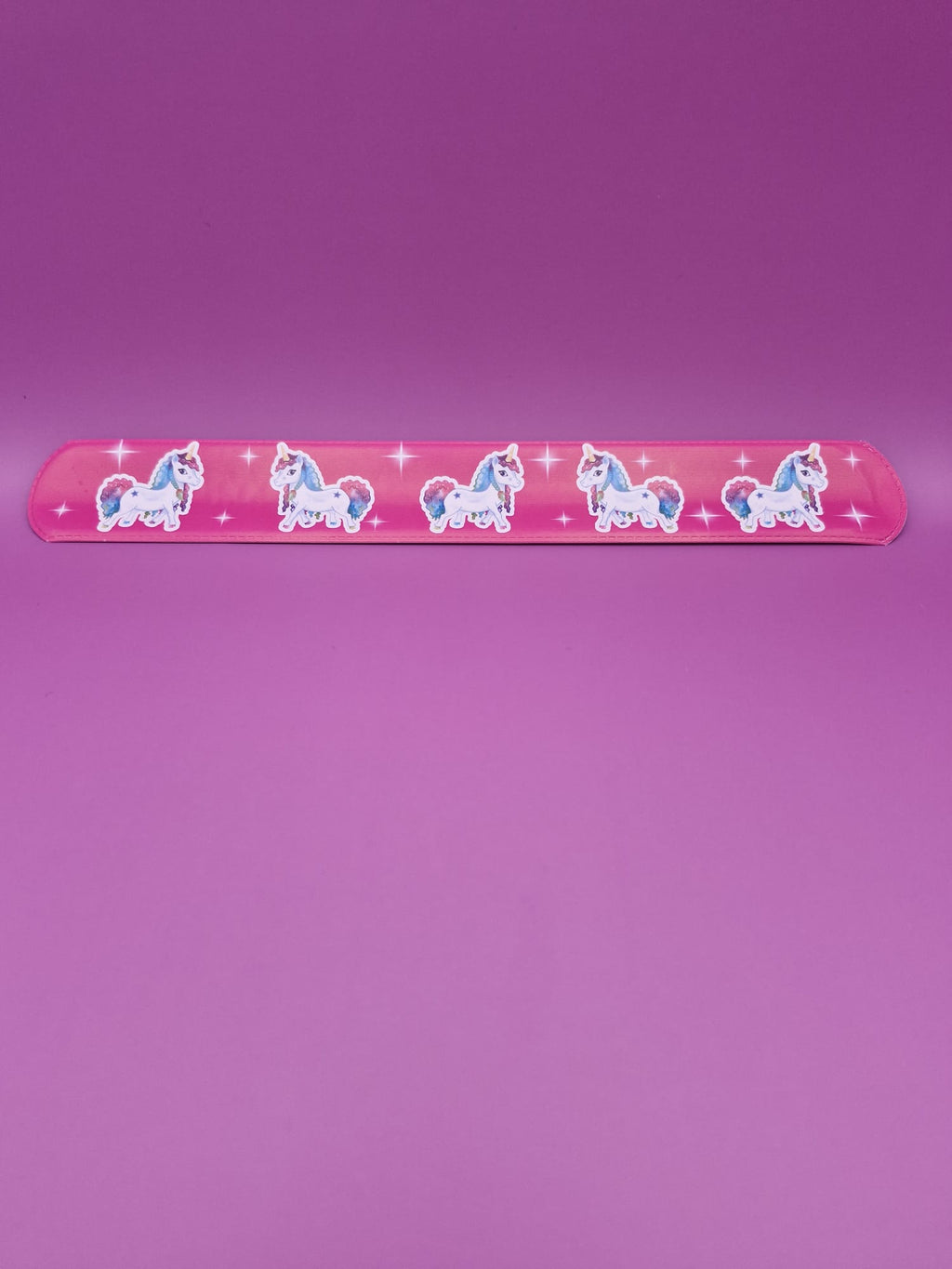 Pink snap bracelet with unicorn designs on a purple background