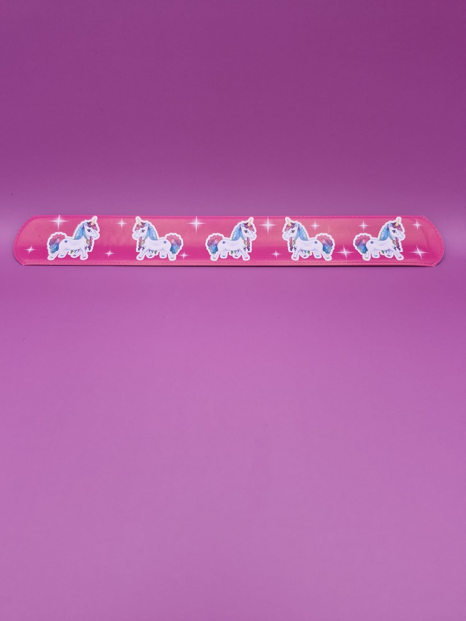 Pink snap bracelet with unicorn designs on a purple background