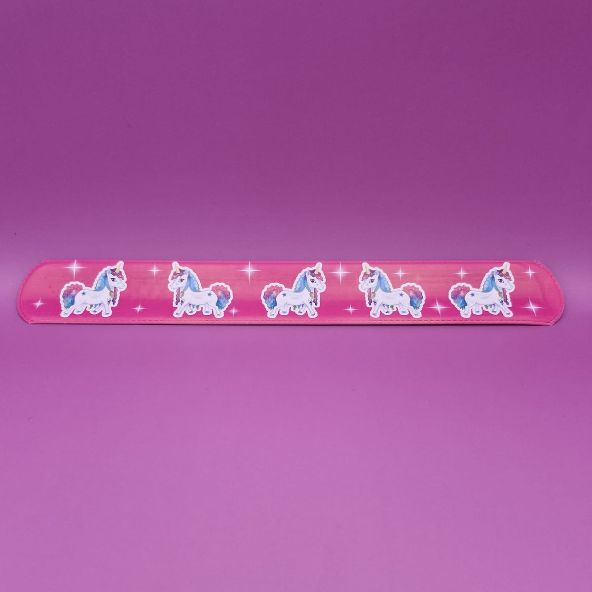Pink snap bracelet with unicorn designs on a purple background