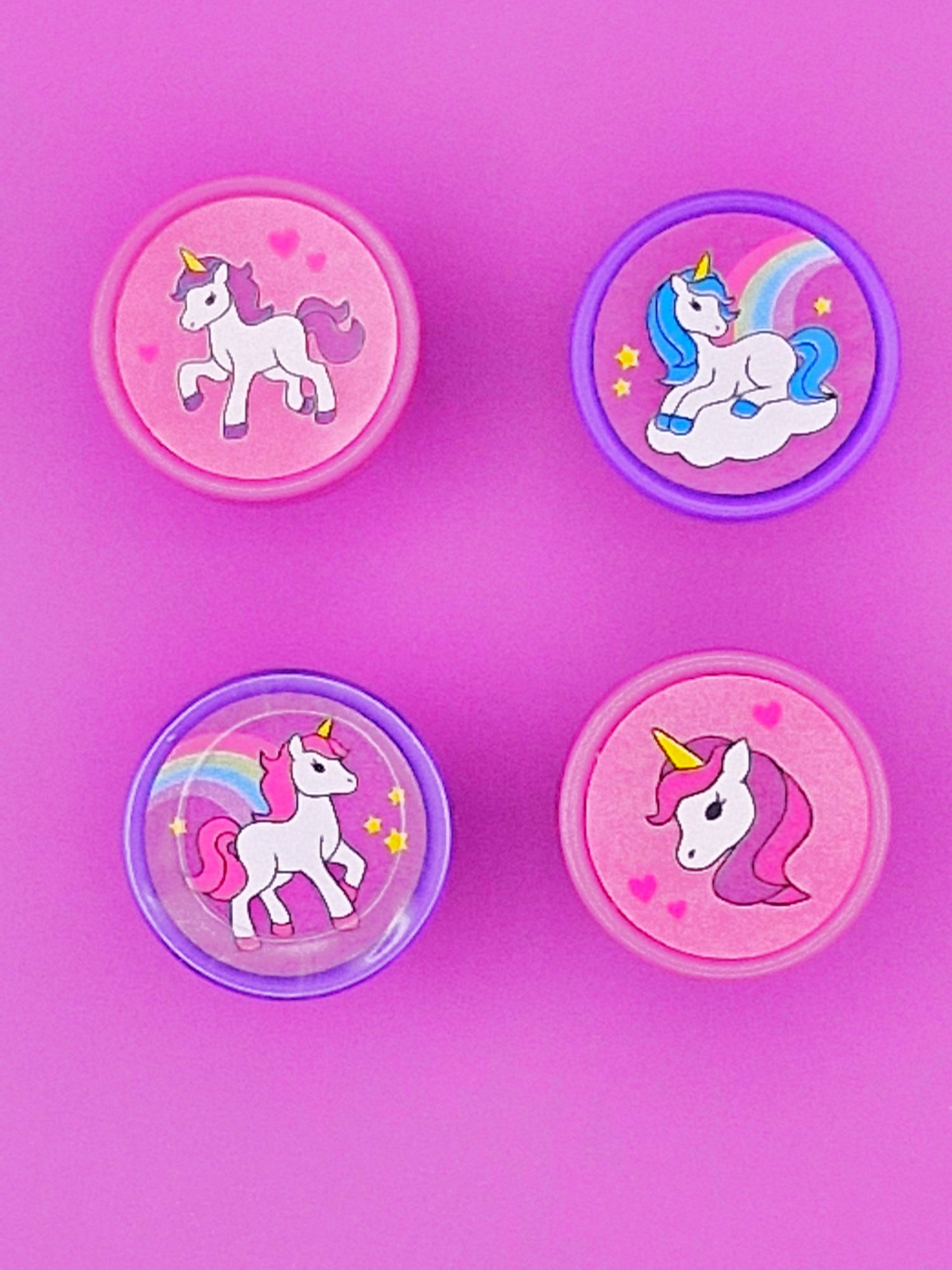 Four stamps with unicorn designs on a pink background